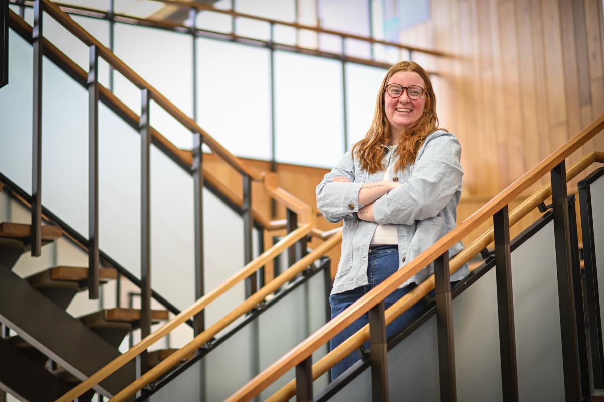 MPA student standing on a staircase, smiling in an academic setting.