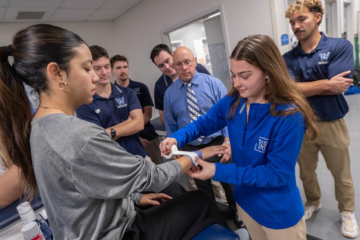 Student practicing wrist taping on a classmate in an athletic training class.