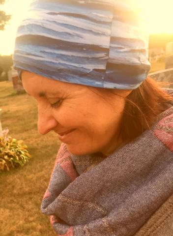 Woman looks down with sun behind her