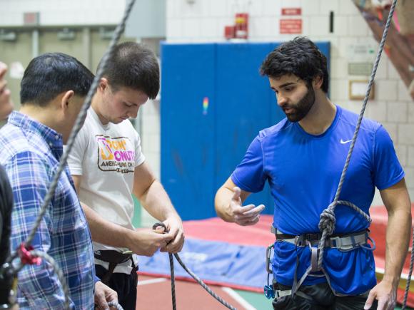 Students in an adventure education course teaching each other how to tie ropes.
