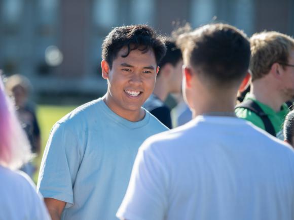 Two students chatting on the campus green on a sunny day.