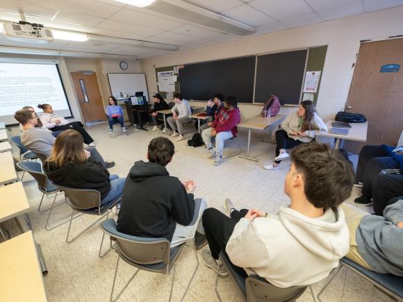 Small psychology class with students and instructor seated in a circle, engaged in discussion.