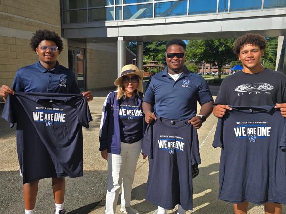 President Linda Thompson stands with three students holding up Westfield State tshirts