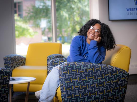 Social work student smiling sitting on a colorful chair.