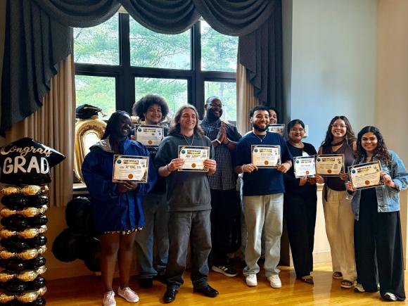 Students smiling holding diplomas.