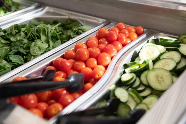 Dining salad bar featuring cucumbers tomatoes and spinach
