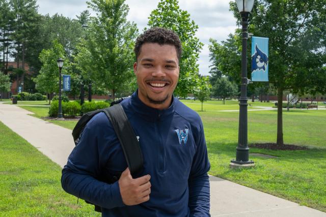 Student smiling while outside on the campus green.