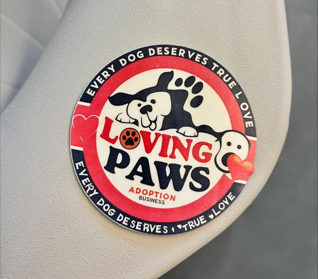 round sticker with the logo: "loving paws adoption: every dog deserves true love" and a photo of a dog  with it's tongue out