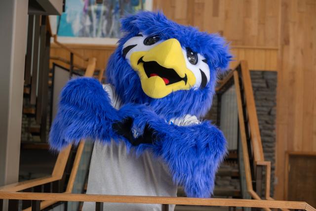 Nestor the mascot makes a heart shape with his hands.