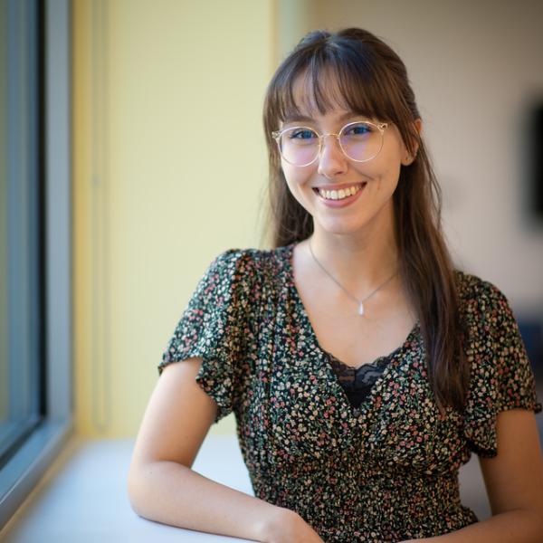 Communication student smiling next to a window.