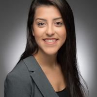 Professional headshot of Thalita Neves smiling at the camera in a gray blazer.